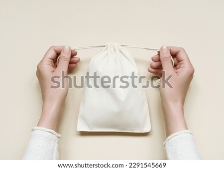 woman closing a small cotton storage pouch. eco-friendly white cotton bag with ties Royalty-Free Stock Photo #2291545669
