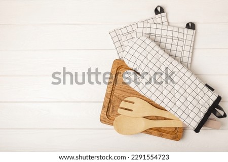 Wooden kitchen utensils, cutting board, potholder and glove on the table, top view. Kitchen Mitten and protective oven mitts on the table. Kitchenware. Kitchen accessories.Close-up.top view. Royalty-Free Stock Photo #2291554723