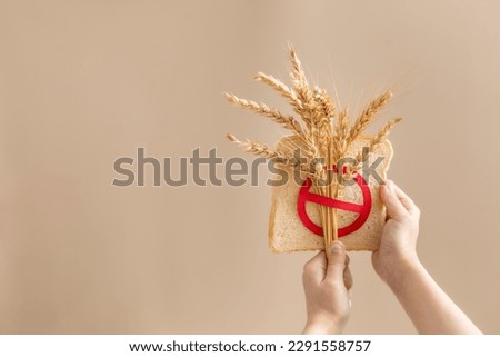 Child hand holding pice of bread with crossed sprinkle. No wheat concept. Celiac world day background. Royalty-Free Stock Photo #2291558757