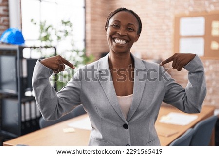 African american woman at the office looking confident with smile on face, pointing oneself with fingers proud and happy.  Royalty-Free Stock Photo #2291565419