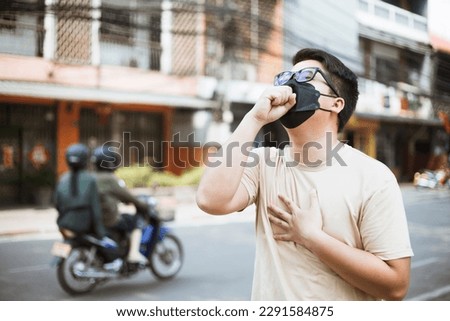 Asian man wearing face mask protect filter against air pollution (PM2.5) and Car pollution on street. Anti smog and virus. Air pollution caused health problem. Environmental pollution concept. Royalty-Free Stock Photo #2291584875