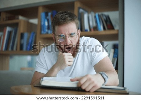 Portrait of tired overworked guy, exhausted young man in glasses college or university student is study hard in library, prepare to exam, lesson