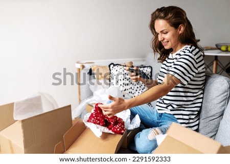 Curly woman taking picture of online purchase and posting photos on her social media.