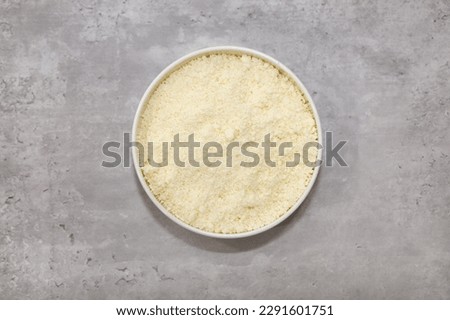 Top view of a bowl with grated Mexican Cotija cheese for food garnishing.