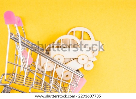 Wooden car model in the shopping cart on yellow background for buy car concept.