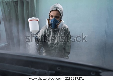 Automobile repairwoman servicing car in painting booth Royalty-Free Stock Photo #2291617271