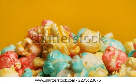 Colored popcorn on a yellow background with copy space