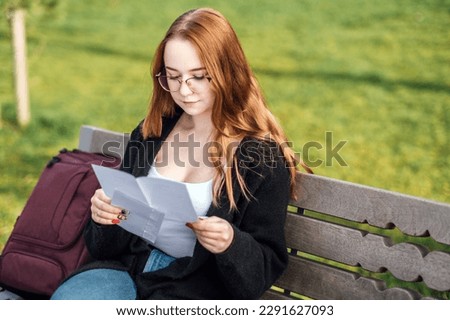 Understanding Student Loan Repayment Options. Pros and Cons of Federal vs Private Student Loans. Young student girl in glasses and with laptop and books reading letter outdoors Royalty-Free Stock Photo #2291627093