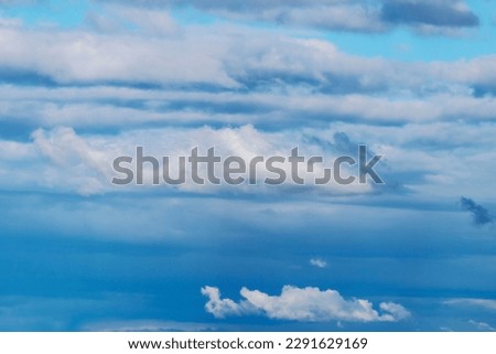 Summer blue sky with gray and white clouds hiding the sun. Winter weather before the storm. Spring winds scatter the clouds in the blue sky. Peace of nature looking at the sky. Moment of relaxation. 