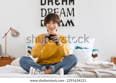 Teenage boy playing video game in bedroom