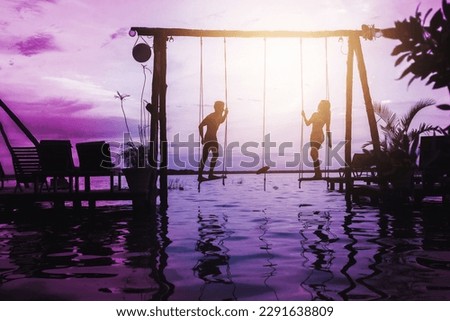 Silhouette of couple on rope swings on the beach during summer vacation