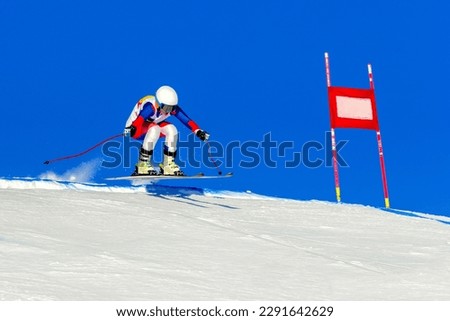 female racer on alpine skiing track, snowy slope on blue sky background, winter sports games