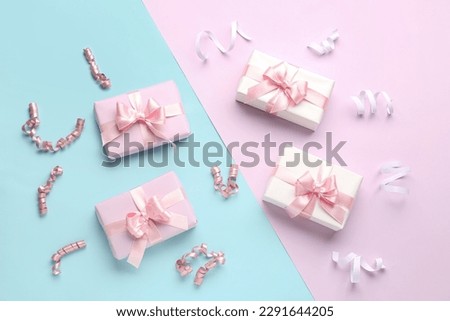 Gift boxes with beautiful bows and serpentine on colorful background