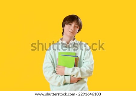 Male student with copybooks on yellow background