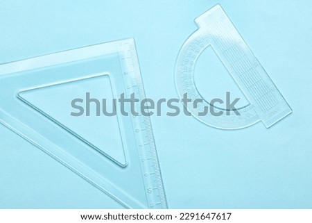Transparent plastic triangle ruler and protractor on blue background