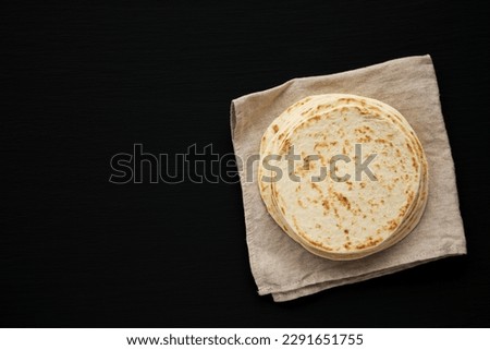 Stack of Whole Wheat Flour Tortillas on a black background, top view. Flat lay, overhead, from above. Copy space. Royalty-Free Stock Photo #2291651755