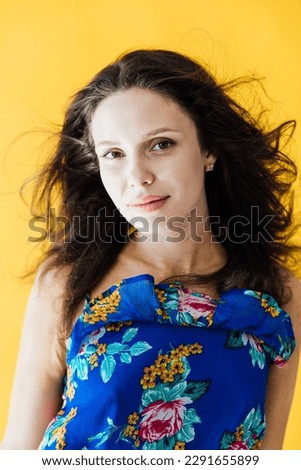 portrait of beautiful woman in a blue floral dress on a yellow background