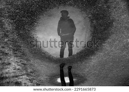 person reflection puddle greyscale dirt road silhouette Royalty-Free Stock Photo #2291665873