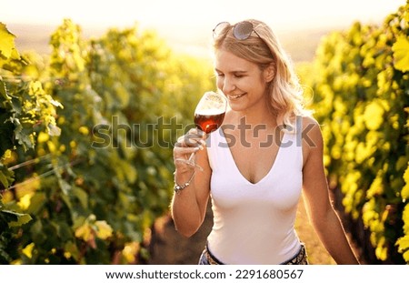 Portrait of a young, millennial woman holding and smelling a glass of organic bio red wine outdoors in a vineyard - Vine-growing, and wine-tasting concept Royalty-Free Stock Photo #2291680567
