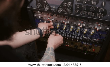 Audio engineer uses audio compressor. Musician changes the volume level, sound settings, creates song with modern professional equipment. Work in the sound recording studio. Music production concept.