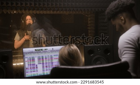 Experienced audio engineer and African American producer work with singer in sound recording studio. Computer screen shows the DAW software interface for creating music. Concept of music production.