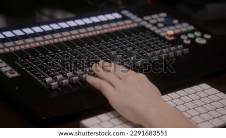 Close up of audio engineer, musician, producer using MIDI controller, mixing board, creating new song or DJ set with modern musical equipment. Work in sound recording studio. Music production concept.