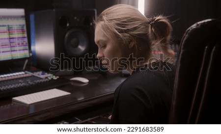 Female sound engineer, musician uses MIDI controller, digital electric piano for creating music. Computer screen shows DAW software interface with sound tracks. Recording studio. Music production.