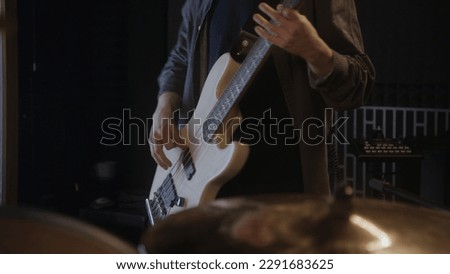 Professional musicians records song in sound recording studio. Male guitarist plays the electric guitar. Close up of drummer playing a drum kit. Work in music recording room. Music production concept.