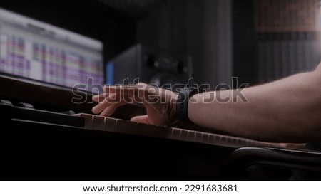 Audio engineer, producer uses MIDI controller, digital electric piano for creating music. Screen showing DAW software interface with sound tracks. Sound recording studio. Music production. Close up.
