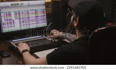 Musical band records song in music recording room. Audio engineer or producer uses computer with professional software and DAW controller for creating music. Sound recording studio. Music production.