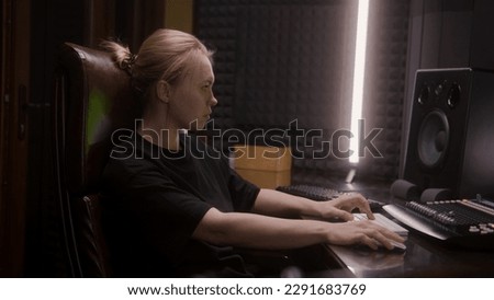Female audio engineer, musician, producer uses MIDI controller, mixing board, creates song or DJ set with modern equipment for creating music. Work in sound recording studio. Music production concept.