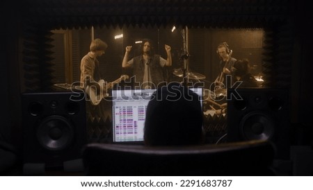 Musical band records song in music recording room. Audio engineer or producer uses computer with program and tools for creating music. Work in the sound recording studio. Music production concept.