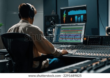 Sound engineer working in music studio with monitors and equalizer screen mixing and mastering tracks