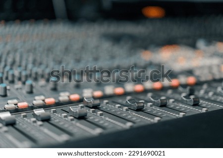 A recording studio control panel mixer with an equalizer faders buttons for broadcasting a recording of song