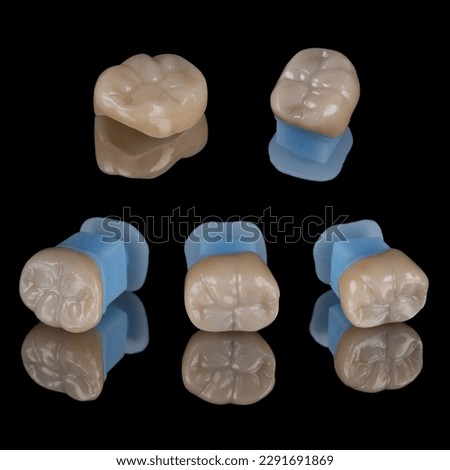 Laboratory pieces of all ceramic dental crown made from Zirconia material placed on blue holder on reflected black acrylic plate