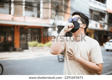 Asian man wearing face mask protect filter against air pollution (PM2.5) and Car pollution on street. Anti smog and virus. Air pollution caused health problem. Environmental pollution concept. Royalty-Free Stock Photo #2291693471