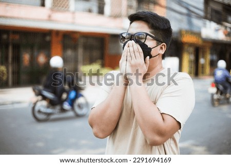 Asian man wearing face mask protect filter against air pollution (PM2.5) and Car pollution on street. Anti smog and virus. Air pollution caused health problem. Environmental pollution concept. Royalty-Free Stock Photo #2291694169