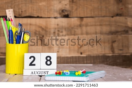 August calendar background with number  28. Stationery pens and pencils in a case on a wooden vintage background. Copy space notepad with pencils and calendar. Planner place for text.