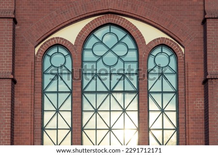 A brick facade with ornate windows that reflect the setting sun.