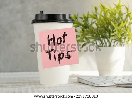 Keyword HOT TIPS - business concept text on sticky paper on cup coffee and keyboard, green flowers
