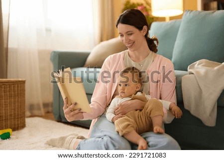 Young mother reading a story to her baby boy at home