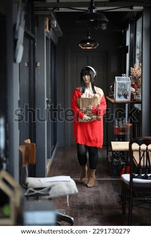 Portrait of a beautiful young woman Cosplay with red sweater with bread in shopping bag at corridor
