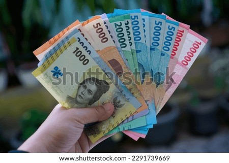 Hand holding Indonesian money isolated on bokeh background Royalty-Free Stock Photo #2291739669