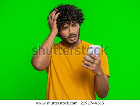 Indian man use mobile cell phone typing browsing, loses becoming surprised sudden lottery results, bad fortune, loss, fail. Handsome hindu guy isolated alone on green chroma key background, indoors