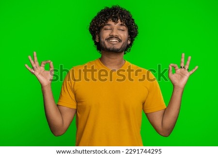 Keep calm down, relax, inner balance. Young indian man breathes deeply with mudra gesture, eyes closed, meditating with concentrated thoughts peaceful mind. Hindu guy isolated on chroma key background