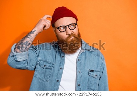 Photo of uncertain funky guy dressed denim jacket eyeglasses finger head looking empty space isolated orange color background Royalty-Free Stock Photo #2291746135
