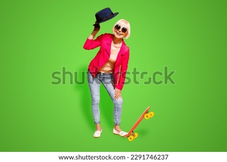Full-body full-legh portrait of happy granny with a board for skating isolated on vivid yellow background