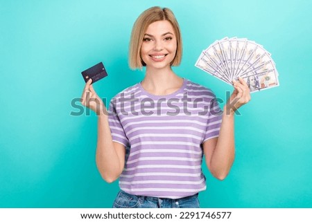 Photo of young shopaholic lady wear stylish clothes hold privat bank card cash money enjoy spend them isolated on cyan color background