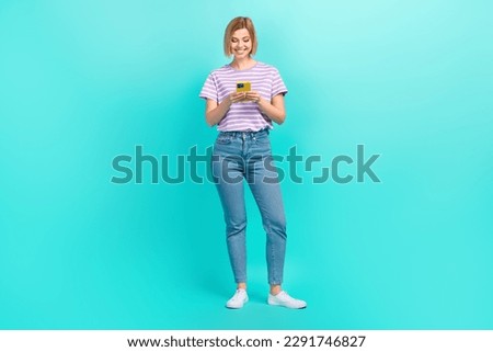 Full length photo of young girl use phone texting her boyfriend write email wear denim jeans t-shirt isolated on cyan color background