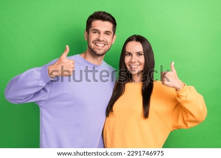 Photo of adorable confident boyfriend girlfriend wear sweatshirts showing thumbs up isolated green color background
